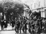 <p>British soldiers celebrate their victory—and the fact that they'll be returning home soon—by waving a British flag in the streets of Paris. </p>