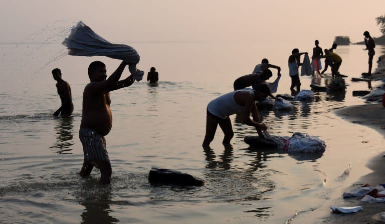 <p>In this photograph taken on June 4, 2016, Indian dhobiwallahs or washermen do laundry on the banks of the River Bhramaputra in Guwahati. By the time the working day begins in northeast India on the longest day of the year, the sun is already high in the sky and the heat is nearing its peak — because clocks across the vast country are set to the same hour. </p>