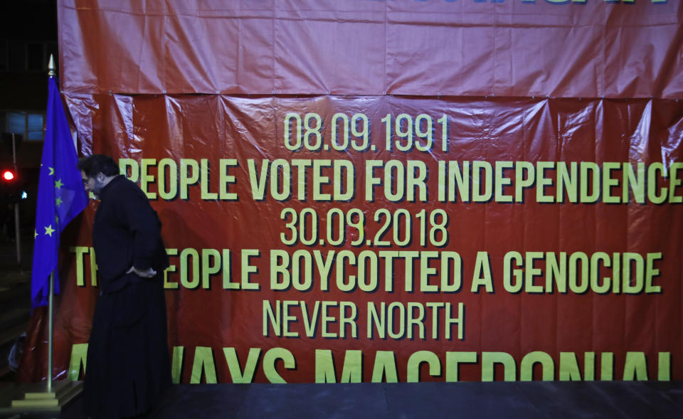 A priest, supporter of a movement for voters to boycott the referendum, moves an EU flag on a stage for a gathering of supporters in central Skopje, Macedonia, after election officials gave low turnout figures before polls closed, Sunday, Sept. 30, 2018. The crucial referendum o accepting a deal with Greece to change the country's name to North Macedonia and pave the way for NATO membership, attracted tepid voter participation Sunday. (AP Photo/Thanassis Stavrakis)