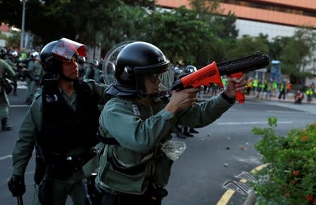 A police officer aims as anti-government protesters demonstrate in Sha Tin