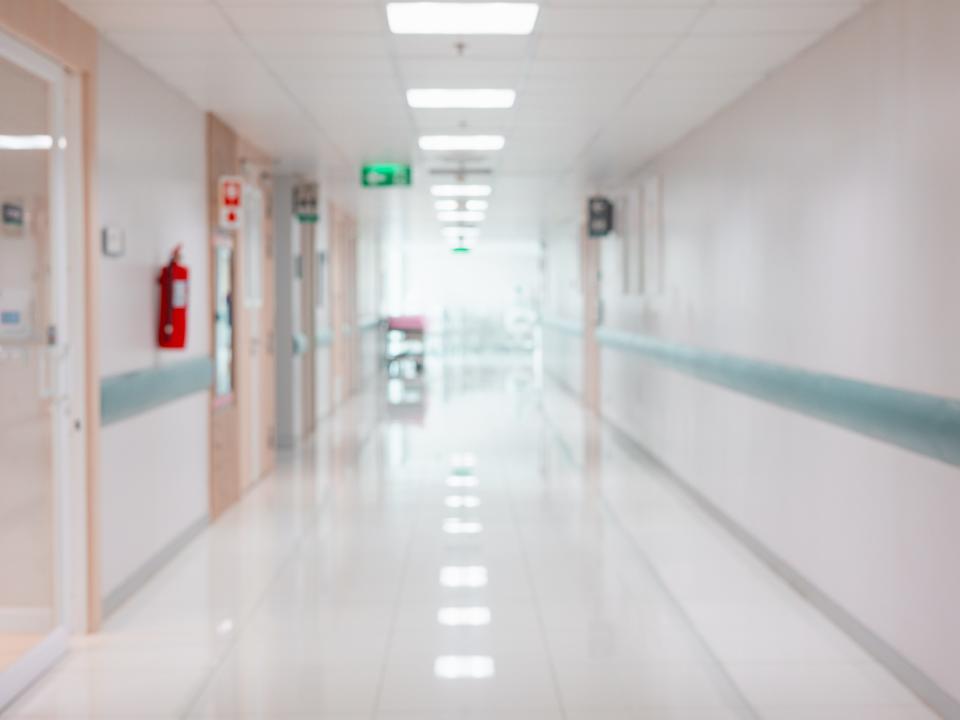 An empty hospital hallway with a bright exit sign next to a doorway.