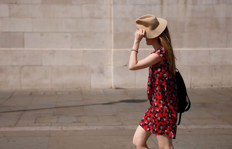 Una mujer utiliza un sombrero para protegerse del sol en Trafalgar Square durante el calor en Londres