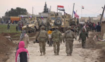 FILE - In this frame grab from video, Russian, Syrian and others gather next to an American military convoy stuck in the village of Khirbet Ammu, east of Qamishli city, Syria, Feb. 12, 2020. Political observers say Russia’s brazen Syria intervention emboldened Putin, giving him a renewed Middle East foothold and helped pave the way for his current attack on Ukraine. (AP Photo, File)