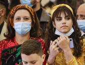 Faithful wait for Pope Francis to arrive at a meeting with the Qaraqosh community at the Church of the Immaculate Conception, in Qaraqosh, Iraq, Sunday, March 7, 2021. A small Christian community returned to Qaraqosh after the war where they rebuilt their church that had been used as a firing range by IS. (AP Photo/Andrew Medichini)