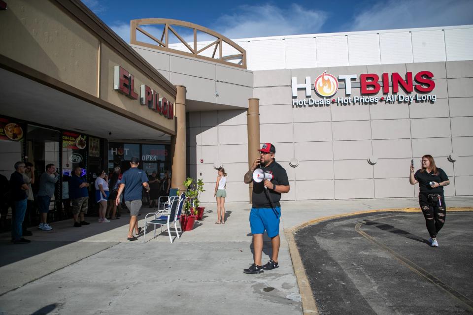 Hotbins manager Carlos Quezada makes announcements to the line of customers before the store's 9 am opening on Friday, Aug. 11, 2023, in Fort Myers.