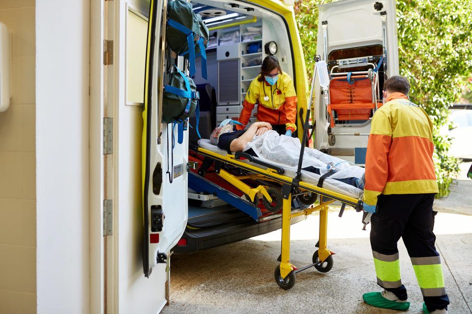 Two EMT workers moving someone on a stretcher into an ambulance