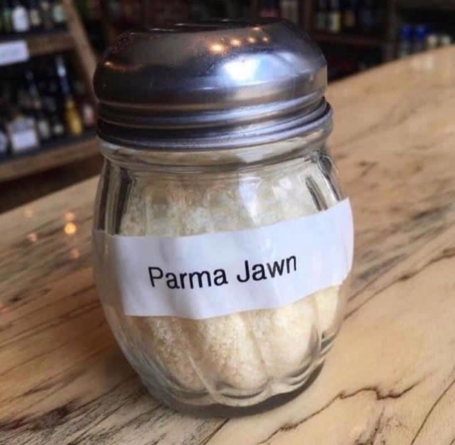 A shaker filled with grated cheese labeled "Parma Jawn" placed on a bar countertop