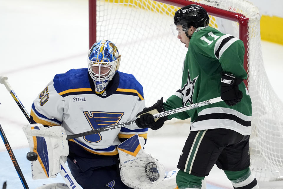 St. Louis Blues goaltender Jordan Binnington (50) deflects a shot with his arm pad under pressure from Dallas Stars center Logan Stankoven (11) during the second period of an NHL hockey game in Dallas, Wednesday, April 17, 2024. (AP Photo/Tony Gutierrez)