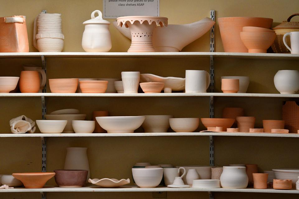 Some of the pottery students' clayware in various stages of completion on shelves at the Worcester Center for Crafts.