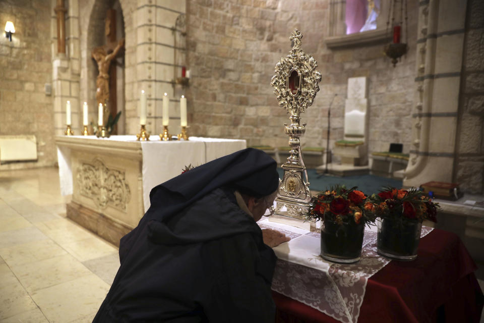 A Christian nun prays next to a wooden relic believed to be from Jesus' manger at the Notre Dame church in Jerusalem, Friday, Nov. 29, 2019. Christians are celebrating the return to the Holy Land of a tiny wooden relic believed to be from Jesus' manger nearly 1,400 years after it was sent to Rome as a gift to the pope. (AP Photo/Mahmoud Illean)