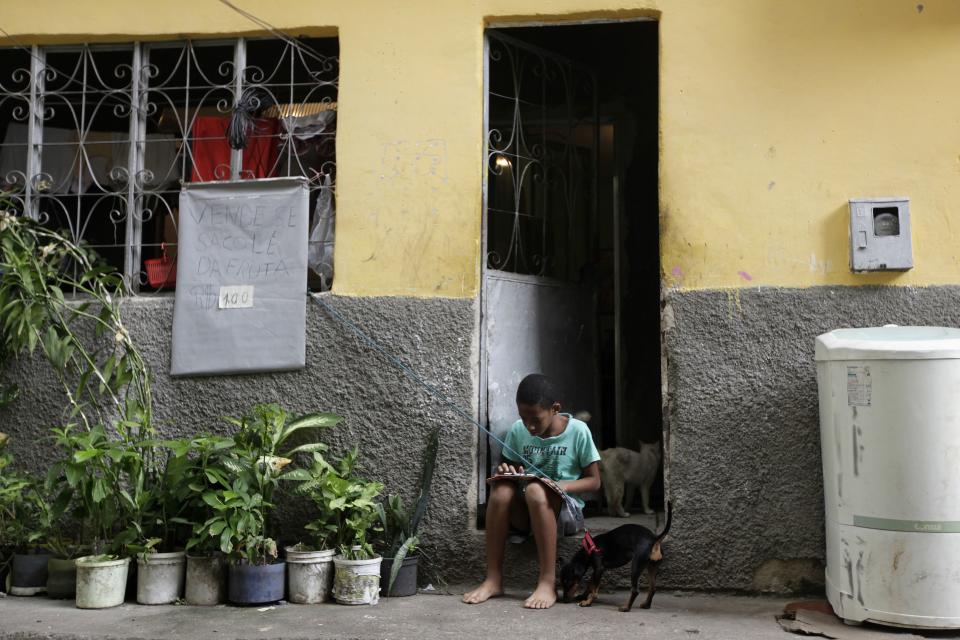 A boy plays on his tablet outside his house at the Mare slums complex in Rio de Janeiro