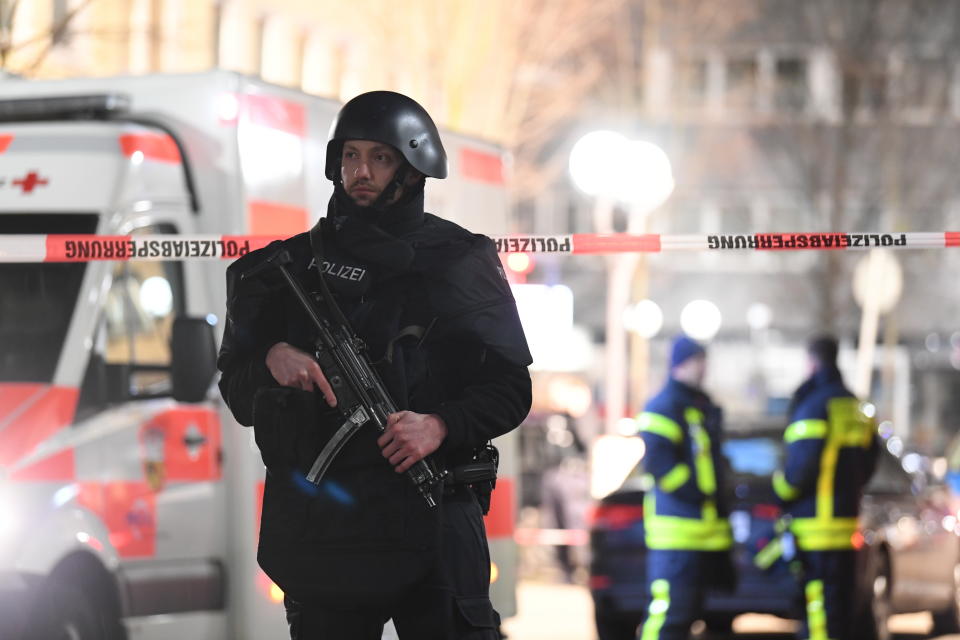 A police officer stands guard near the scene in front of a restaurant after a shooting in central Hanau, Germany Thursday, Feb. 20, 2020. Eight people were killed in shootings in the German city of Hanau on Wednesday evening, authorities said.  (Boris Roessler/dpa via AP)