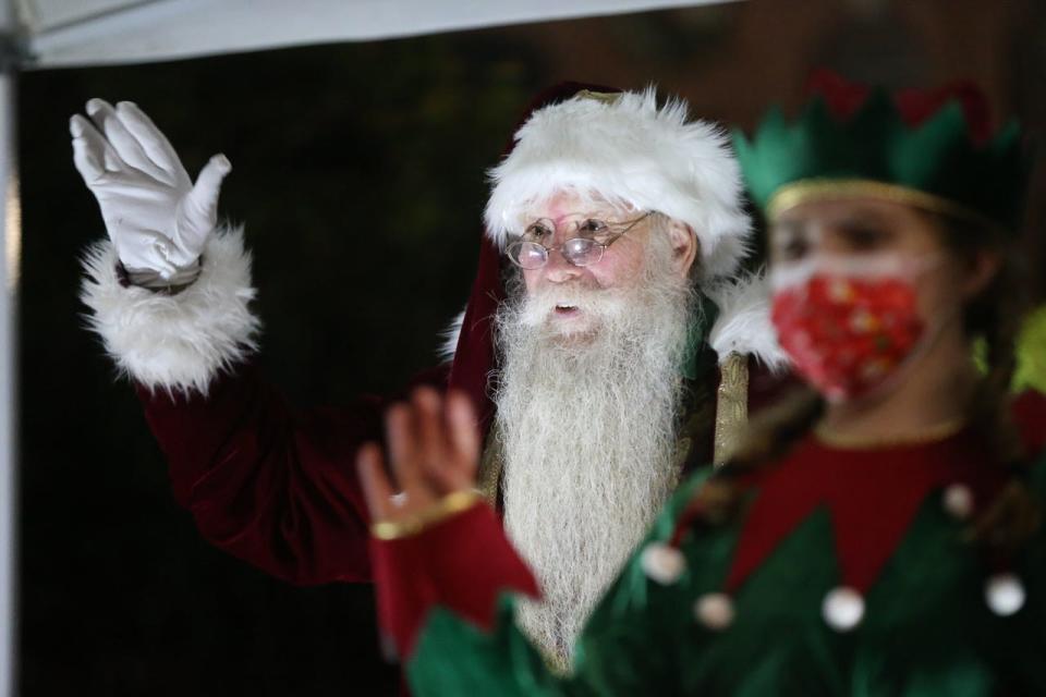 Santa Claus waves to passersby during the Hudson Downtown Business Improvement District Wave-to-Santa event in front of Town Hall in Hudson, Dec. 12, 2020.