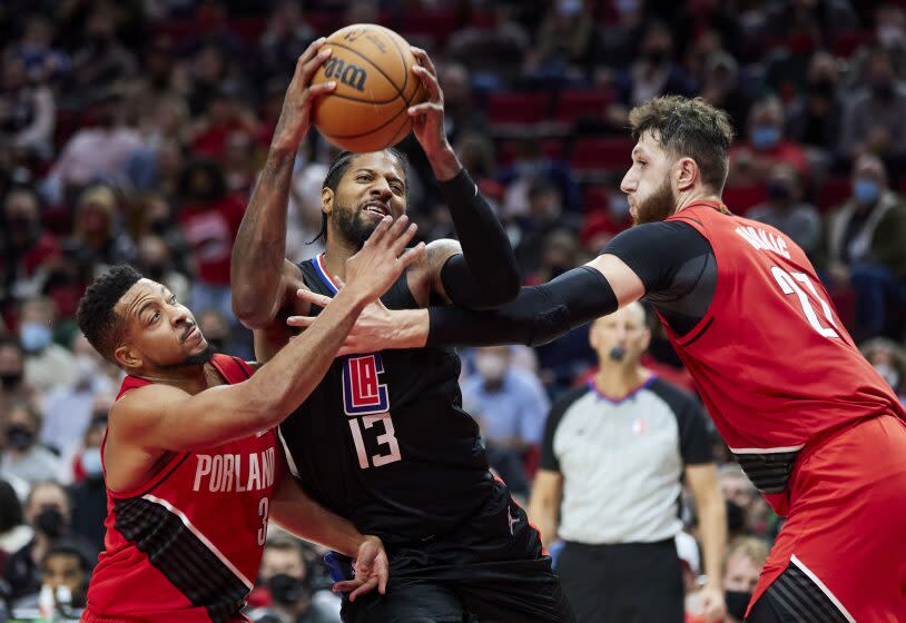 Los Angeles Clippers guard Paul George drives to the basket between Portland Trail Blazers guard CJ McCollum, left, and center Jusuf Nurkic during the second half of an NBA basketball game in Portland, Ore., Friday, Oct. 29, 2021. (AP Photo/Craig Mitchelldyer)