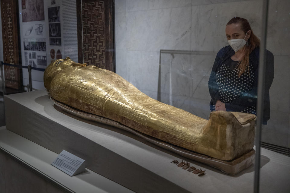 FILE - In this April 24, 2021 file photo, a woman looks at a golden sarcophagus on display at the National Museum of Egyptian Civilization in Old Cairo. As some European countries re-open to international tourists, Egypt has already been trying for months to attract them to its archaeological sites and museums. Officials are betting that the new ancient discoveries will set it apart on the mid- and post-pandemic tourism market (AP Photo/Nariman El-Mofty, File)