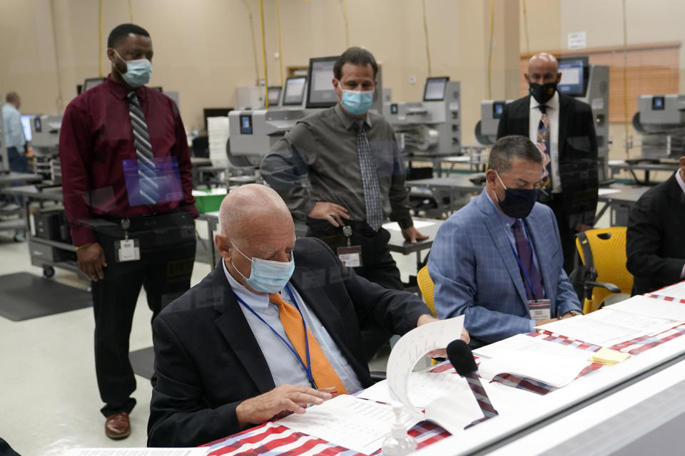 Peter Antonacci, Broward County Supervisor of Elections, left, works with members of the canvassing board on logic and accuracy testing of equipment used for counting ballots, at the Broward Supervisor of Elections Office, Thursday, Sept. 24, 2020, in Lauderhill, Fla. Vote-by-mail ballots will begin going out to residents in Broward County Thursday. (AP Photo/Lynne Sladky)