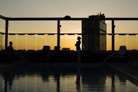 A woman stands and watches the setting sun while standing poolside at the Gansevoort Meatpacking NYC in New York, June 12, 2013. REUTERS/Lucas Jackson