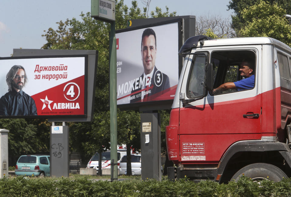 A man drives a truck past electoral posters of the leader of the ruling Social Democrats Zoran Zaev, right, and a poster of the leader of the Leftist party Dimitar Apasiev, in a street in Skopje, North Macedonia on Saturday, July 11, 2020. North Macedonia holds its first parliamentary election under its new country name this week, with voters heading to the polls during an alarming spike of coronavirus cases in the small Balkan nation. (AP Photo/Boris Grdanoski)