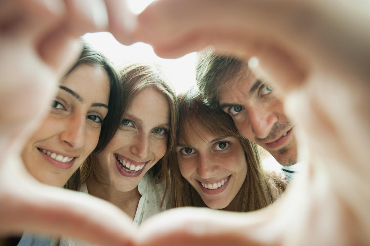 Friends making heart-shaped finger frame, portrait