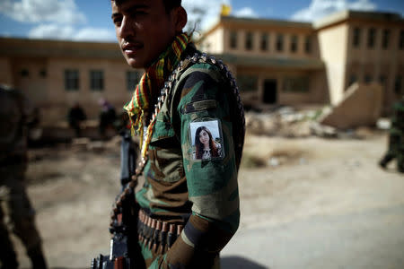 Yazidi Popular Mobilisation Forces (PMF) fighter Hussein Eisso, 21, hangs a photo of Yazidi survivor and United Nations Goodwill Ambassador for the Dignity of Survivors of Human trafficking Nadia Murad on his arm in Kojo, Iraq June 1, 2017. REUTERS/Alkis Konstantinidis