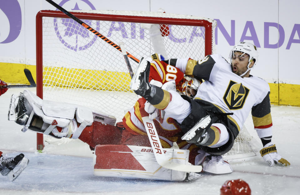 Vegas Golden Knights forward William Carrier, right, slams into Calgary Flames goalie Daniel Vladar (80) during first-period NHL hockey game action in Calgary, Alberta, Monday, Nov. 27, 2023. (Jeff McIntosh/The Canadian Press via AP)