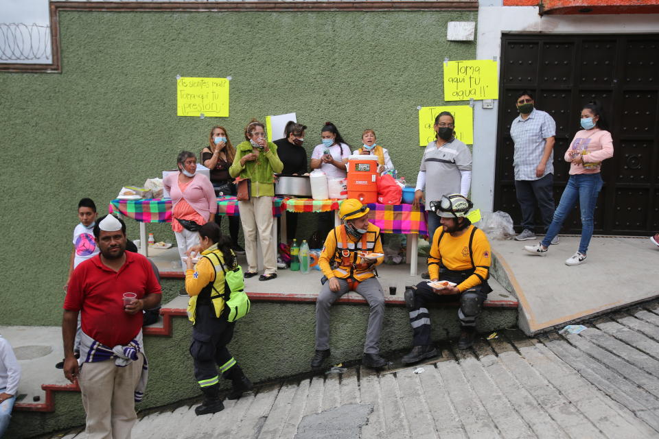 Volunteers offer free food and drink for search and rescue team members at the site of a landslide that brought tons of massive boulders down on a steep hillside neighborhood, in Tlalnepantla, on the outskirts of Mexico City, Saturday, Sept. 11, 2021. A section of the peak known as Chiquihuite gave way Friday afternoon, plunging rocks the size of small homes onto a densely populated neighborhood.
