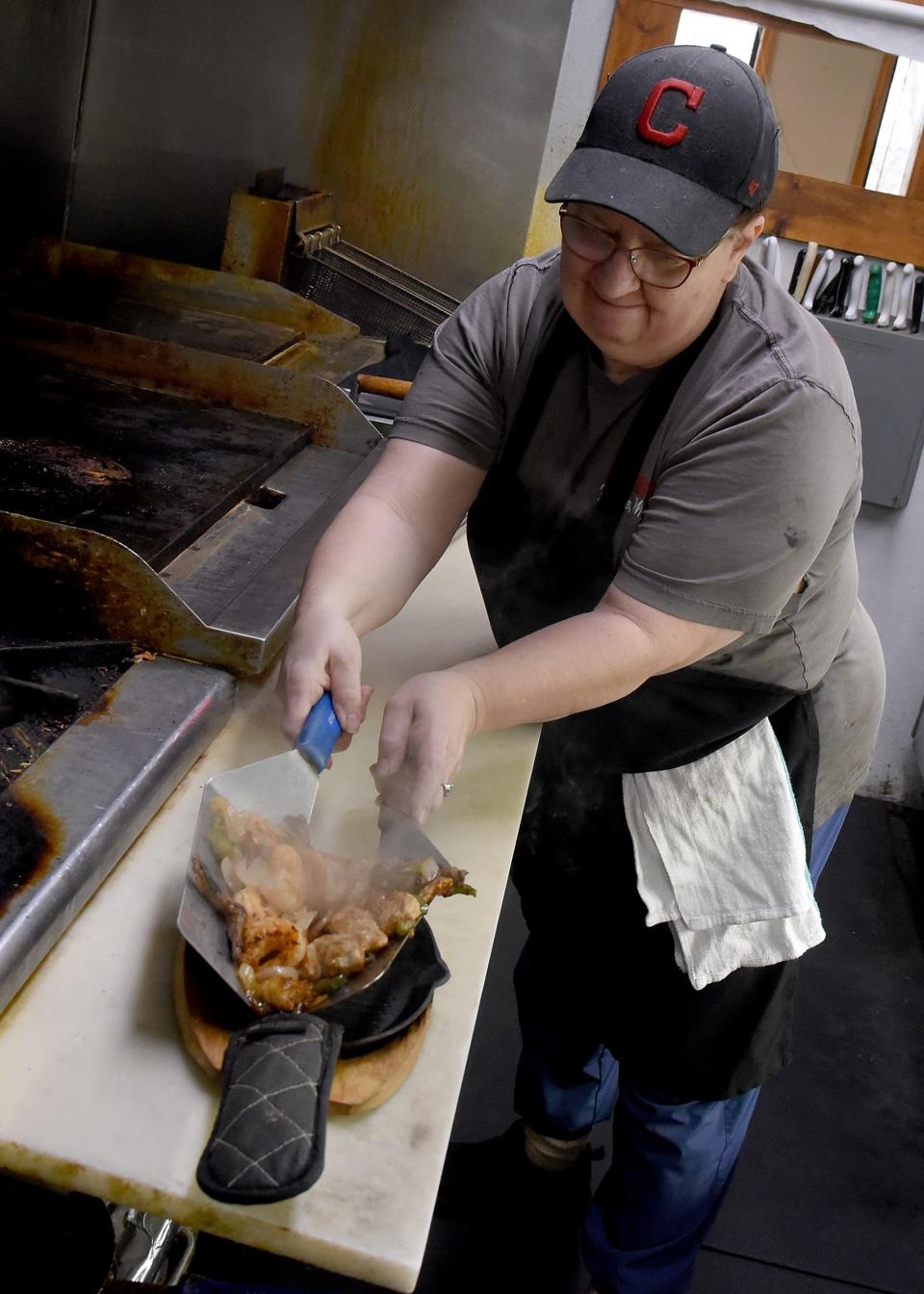 Cook Shirley Parisien places chicken, shrimp and steak with onions and peppers onto a sizzling platter at Cilantro Mexican Restaurant, 388 E. Monroe St. in Dundee. "Everyone here calls me 'Mom,'" said Parisien.