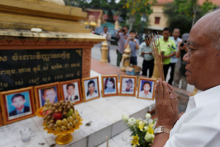 A man prays in front of portraits of victims of a fatal 1997 grenade attack on an opposition rally, which are displayed during a ceremony to remember the victims, at a monument in Phnom Penh, Cambodia, March 30, 2018. REUTERS/Samrang Pring