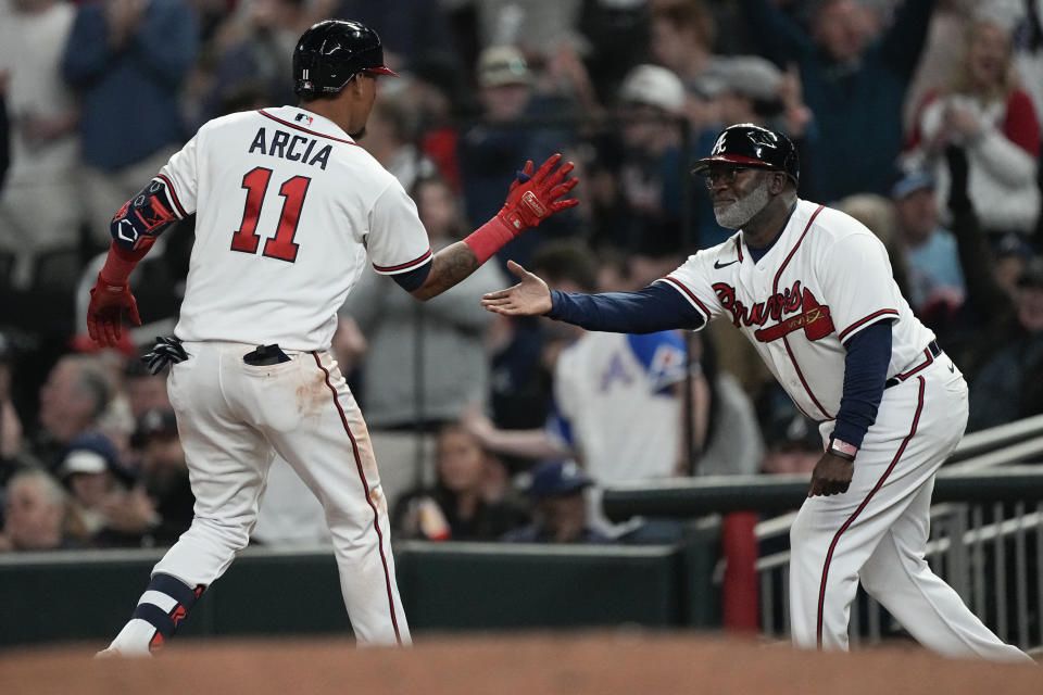 Atlanta Braves' Orlando Arcia (11) celebrates with first base coach Eric Young Sr. (2) after driving in a run with a single in the eighth inning of a baseball game against the Cincinnati Reds, Monday, April 10, 2023, in Atlanta. (AP Photo/John Bazemore)