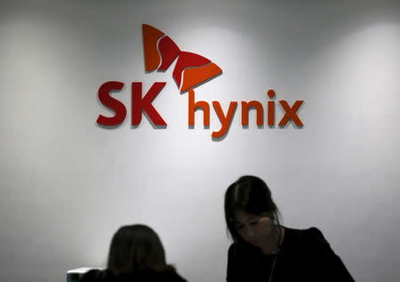 Employees talk in front of the logo of SK Hynix at its headquarters in Seongnam, South Korea, April 25, 2016. REUTERS/Kim Hong-Ji/Files