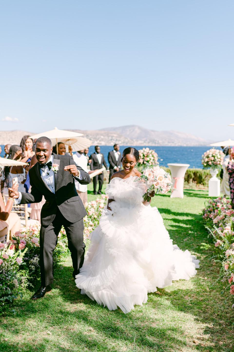 A bride and groom dance as they leave their wedding ceremony overlooking the ocean.