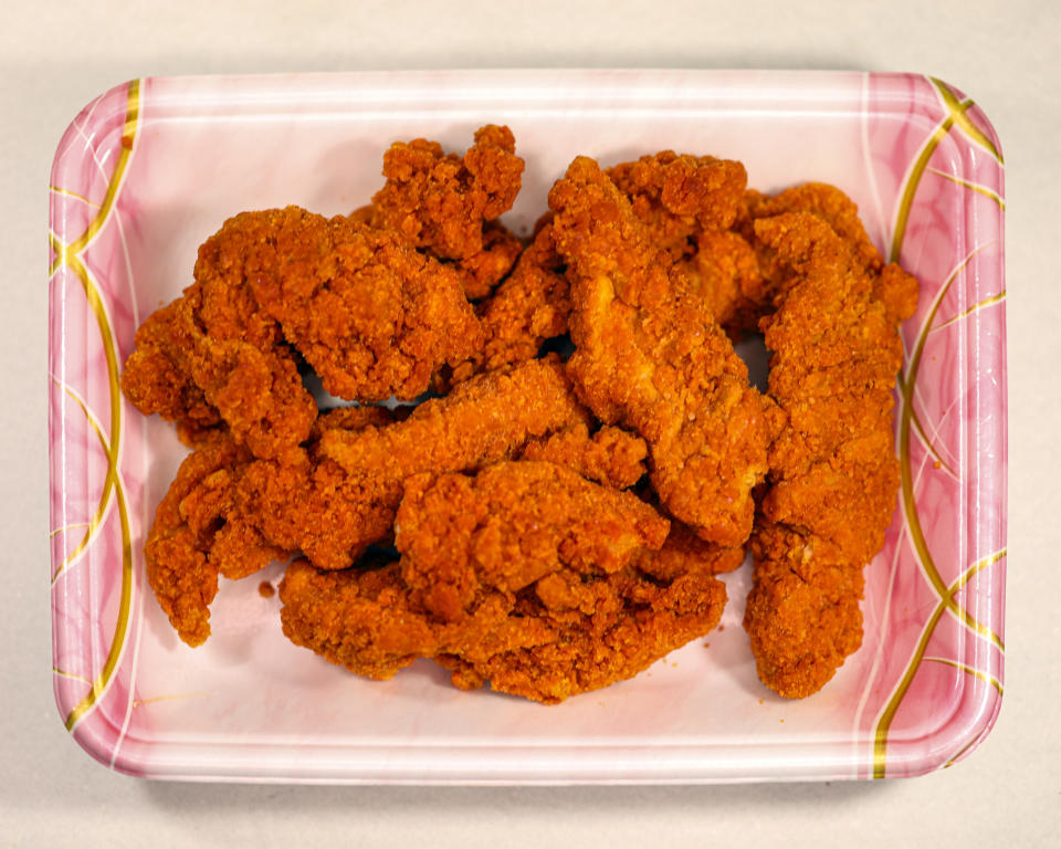A tray of fried chicken tenders on a patterned surface