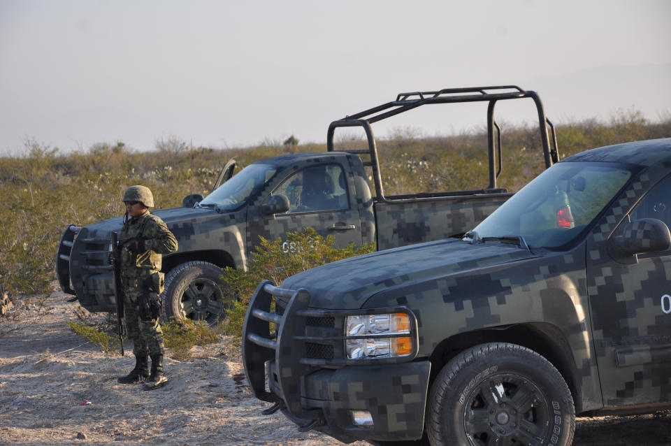 CORRECTS BYLINE TYPO TO VAZQUEZ.- An army soldier stands guard on a dirt road leading to a ranch near the town of Mina, in northern Mexico, Monday, Jan. 28, 2013. At least eight bodies were found in a well near this ranch on Sunday near the site where 20 people went missing late last week, including members of a Colombian-style band, according to a state forensic official. Officials could not confirm whether the bodies belonged to 16 members of the band Kombo Kolombia and their crew, who were reported missing late last week after playing a private show in a bar in the neighboring town of Hidalgo north of Monterrey. (AP Photo/Emilio Vazquez)