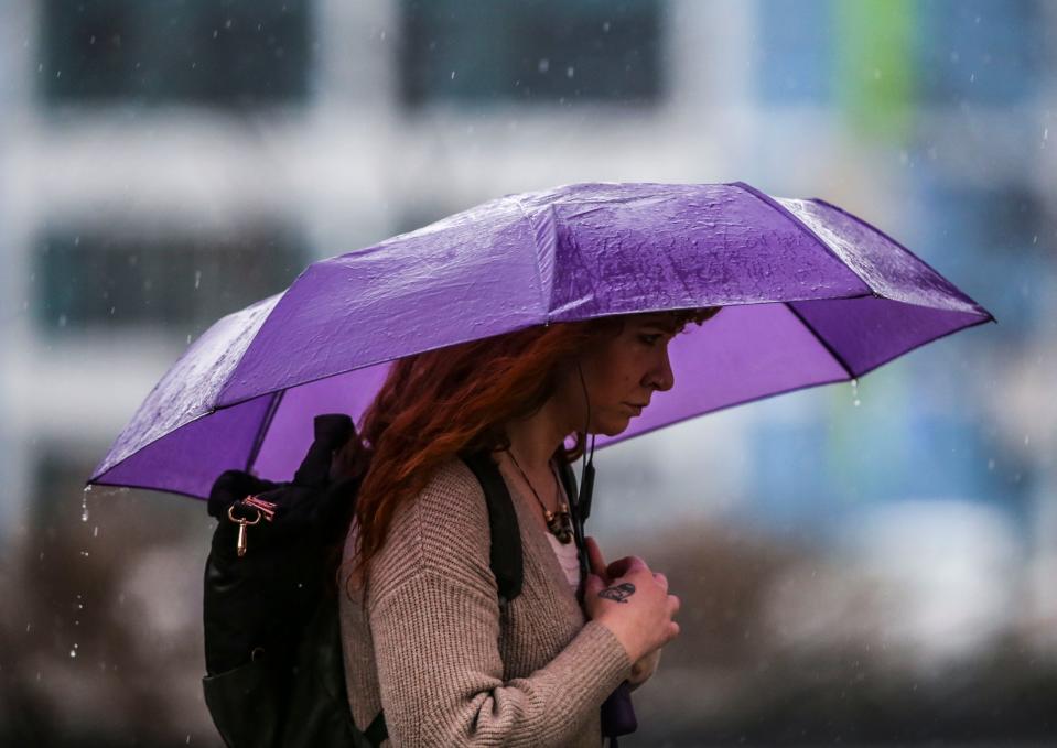 A woman walked near 6th and Market under an umbrellas as rain fell Friday afternoon. March 3, 2023.