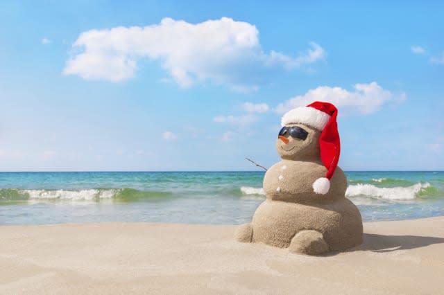 Christmas snowman in santa hat at sandy beach