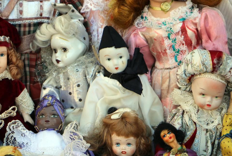 Assorted vintage dolls displayed together, featuring various outfits and expressions