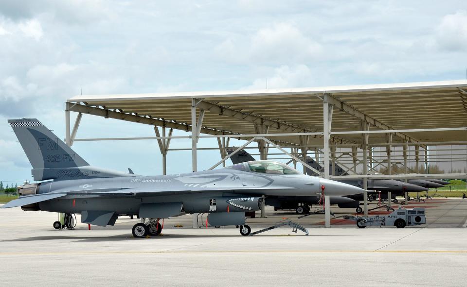 a line of fighter jets with the front aircraft sporting a paint job of a mako shark