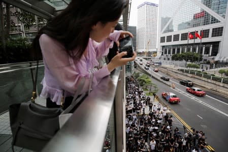 A office worker takes photos of the activists' march to major international consulates in an attempt to rally foreign governments' support for their fight against a controversial extradition bill in Hong Kong