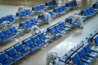 Workers in protective suits disinfect a waiting hall at the Wuhan Railway Station which has been closed due to the novel coronavirus disease (COVID-19) outbreak, in Wuhan