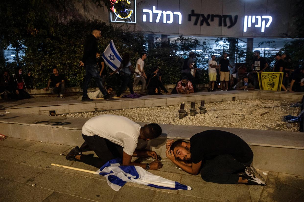 Jewish nationalist demonstrators take cover during a barrage of rockets fired from the Gaza Strip toward central Israel, in the Israeli town of Ramla on Tuesday, May 11, 2021.