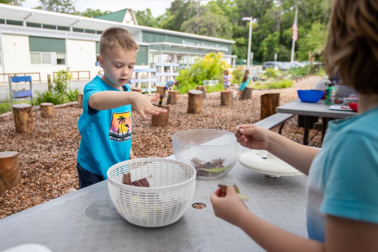 Eli Badenberg helps a friend make a salad in the garden class at the School of Arts and Sciences on Thomasville Road on Thursday, April 18, 2024.