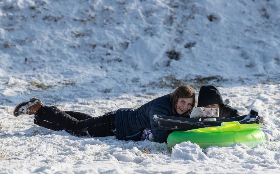 Caroline Pape, left and Anabel Crush record a video of the two of them rolling down Reservoir Hill in the snow. Jan. 28, 2021