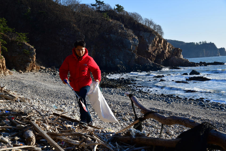 Kang Dong Wan, 48, a professor at South Korea's Dong-A University, picks up trash from North Korea on beach of Yeonpyeong Island, South Korea on Dec. 21, 2021. Kang has turned to a different way of collecting information about secretive North Korea as pandemic restrictions make it harder for outsiders to find out what's life like for North Koreans.(Courtesy of Pro. Kang Dong Wan via AP)