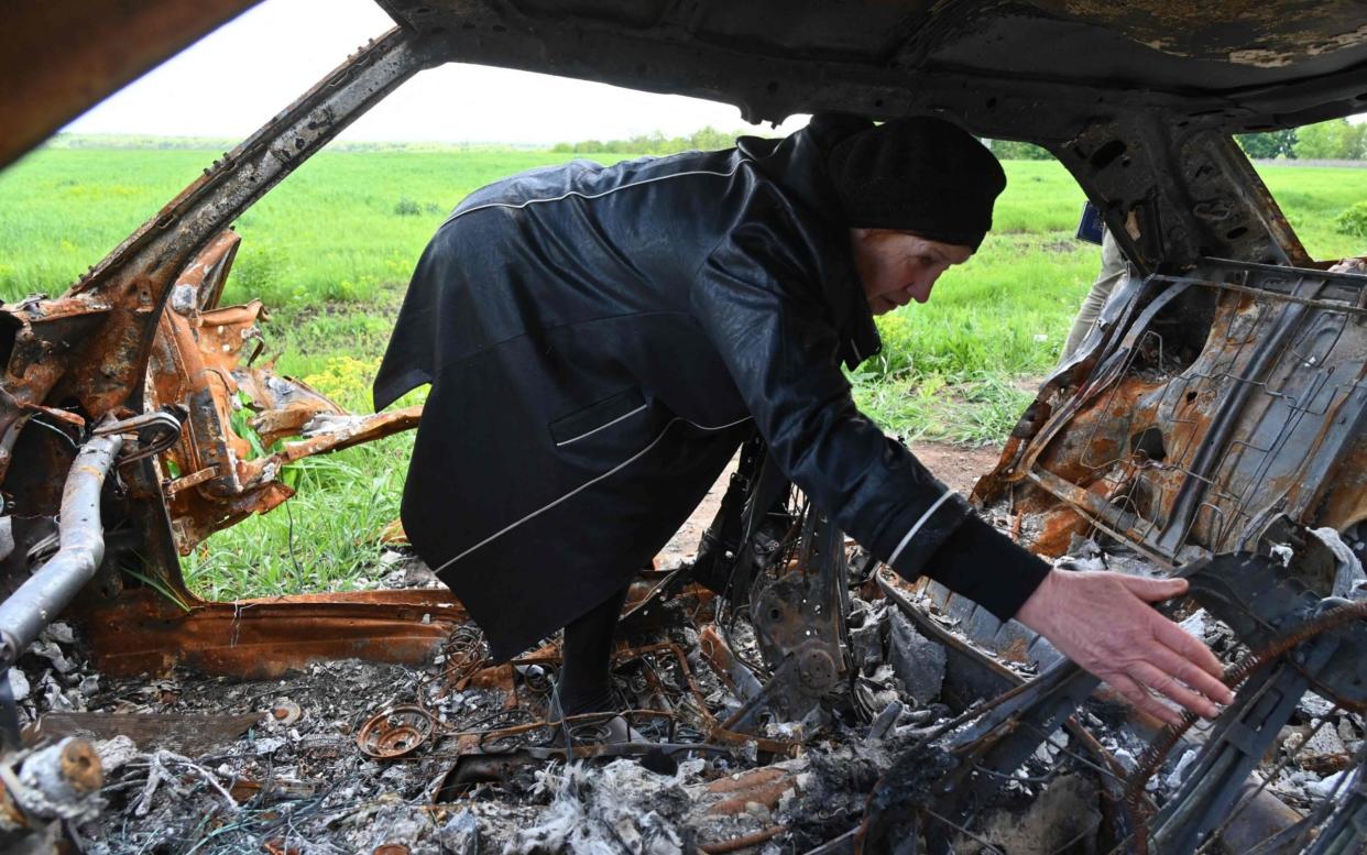 Olga Khomenko, 67, looks for remains of her son, a 38-year-old who died when his car was hit by a shell from a Russian tank outside the village of Mala Rogan near Kharkiv in eastern Ukraine - SERGEY BOBOK/AFP