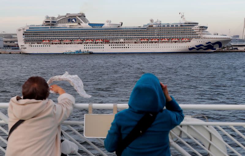 Tourists on a sightseeing cruise ship wave to passengers of the cruise ship Diamond Princess, which is anchored at Daikoku Pier Cruise Terminal in Yokohama