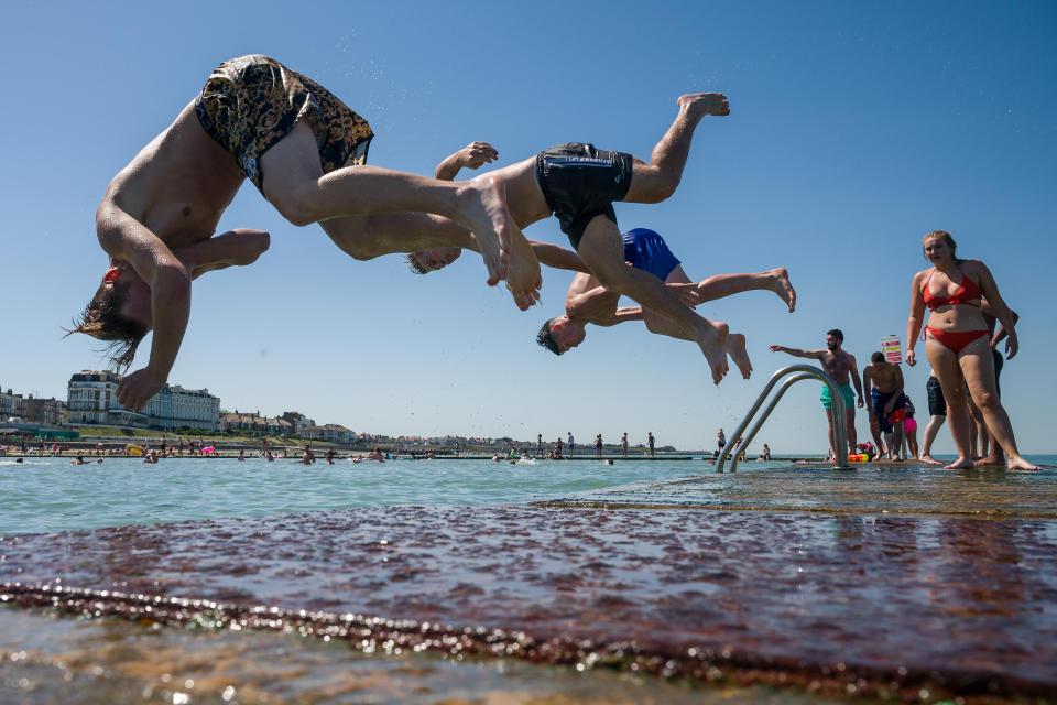 Boys somersault into the water from the lido jetty wall at Margate beach in Margate