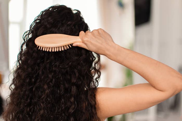 A hairbrush being used to comb through long curly hair