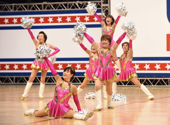 In this picture taken on March 26, 2016 84-year old Fumie Takino (2nd R), leader of middle-aged and elderly women cheerleading group "Japan Pom Pom", and members perform during the national cheerleading and dance championship 2016 of the United Spirit Association (USA) Japan in Chiba, a suburb of Tokyo. Strutting her stuff in a gold-hemmed mini-skirt, white leather boots and shaking silver pom-poms, octogenarian Fumie Takino has discovered her elixir of youth -- cheerleading. Takino and her troupe of spirited grannies tweak the nose of old age, even if their rambunctious routine to the song "Dreamgirls" leaves them painfully out of breath and their pink tank tops dripping with sweat. / AFP / TORU YAMANAKA / TO GO WITH AFP STORY: "JAPAN-ELDERLY-CHEERLEADING" FEATURE by Harumi OZAWA (Photo credit should read TORU YAMANAKA/AFP/Getty Images)
