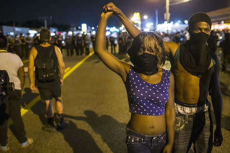 Two anti-police demonstrators walk away from a line of St Louis County police officers during protests in Ferguson, Missouri August 11, 2015. REUTERS/Lucas Jackson