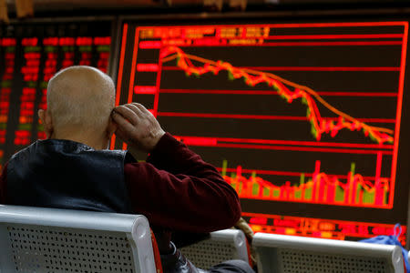 An investor sits in front of a board showing stock information at a brokerage office in Beijing, China, December 7, 2018. REUTERS/Thomas Peter/Files